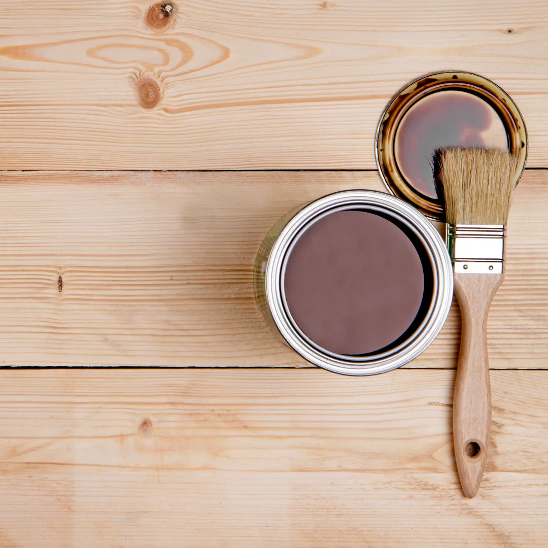 Paint can with brown paint and a brush on a wooden surface for a Build&Bond DIY furniture project